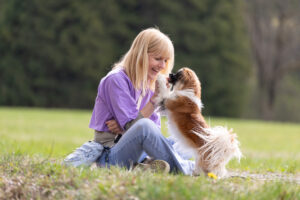 Christine Caspar sitzt mit Hund im Gras